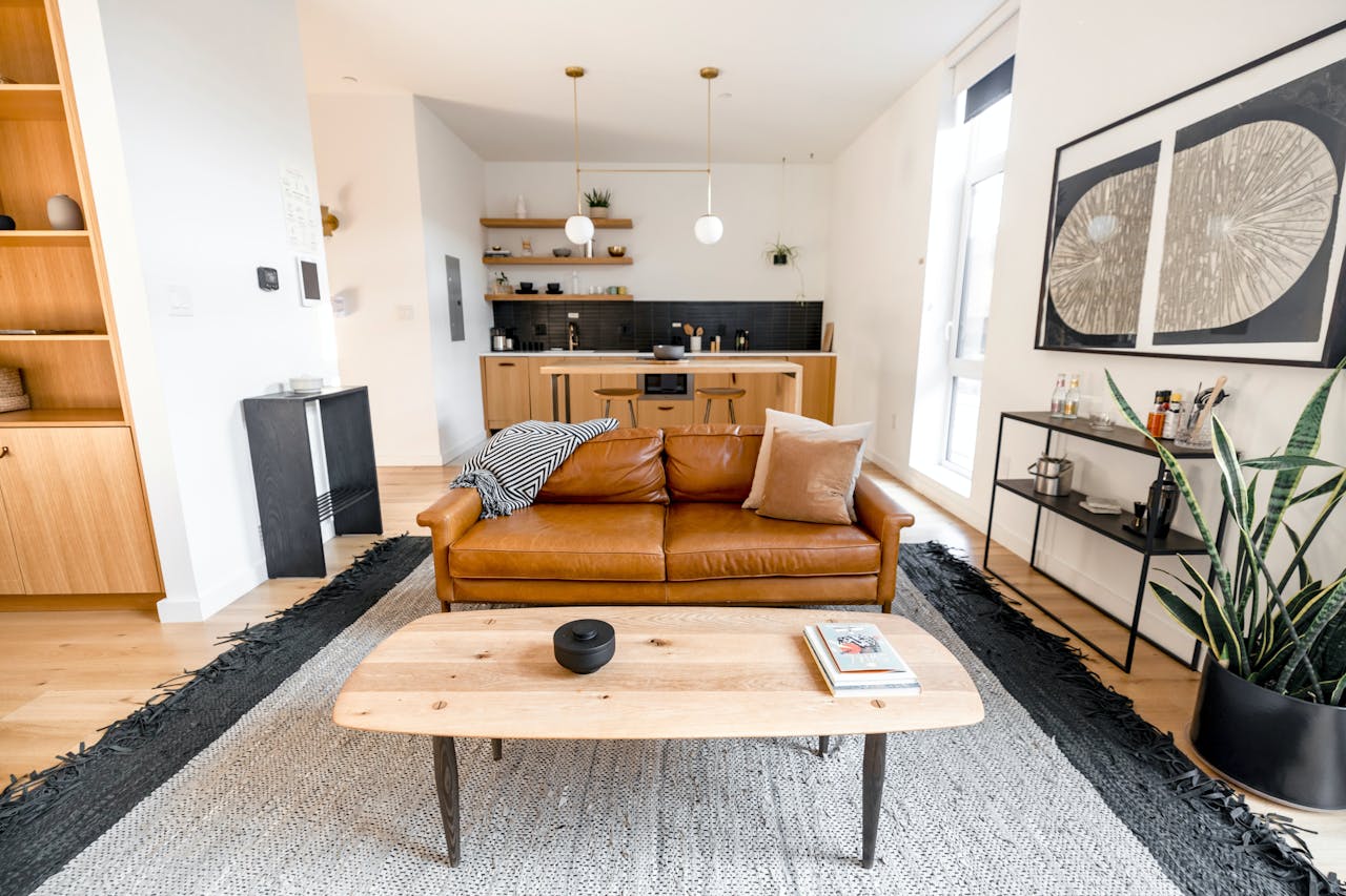 gallery-4 Stylish modern living room with a leather sofa, kitchen area, and decor elements.